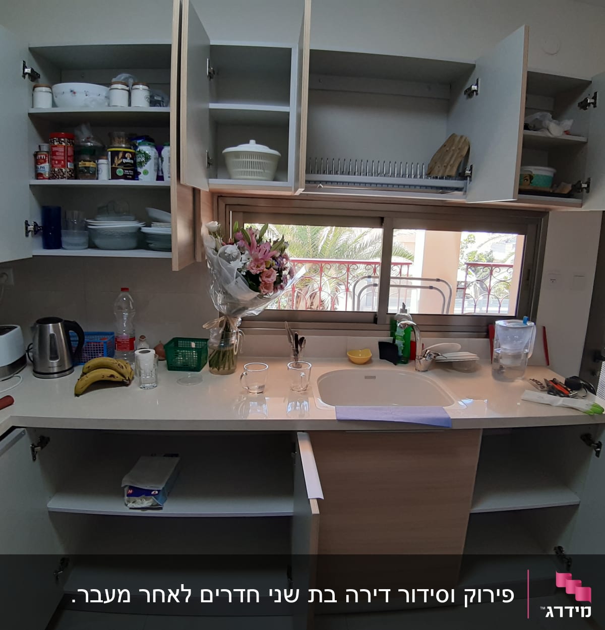 מטבח עם ארונות פתוחים, כלים ומוצרי ניקוי על השיש